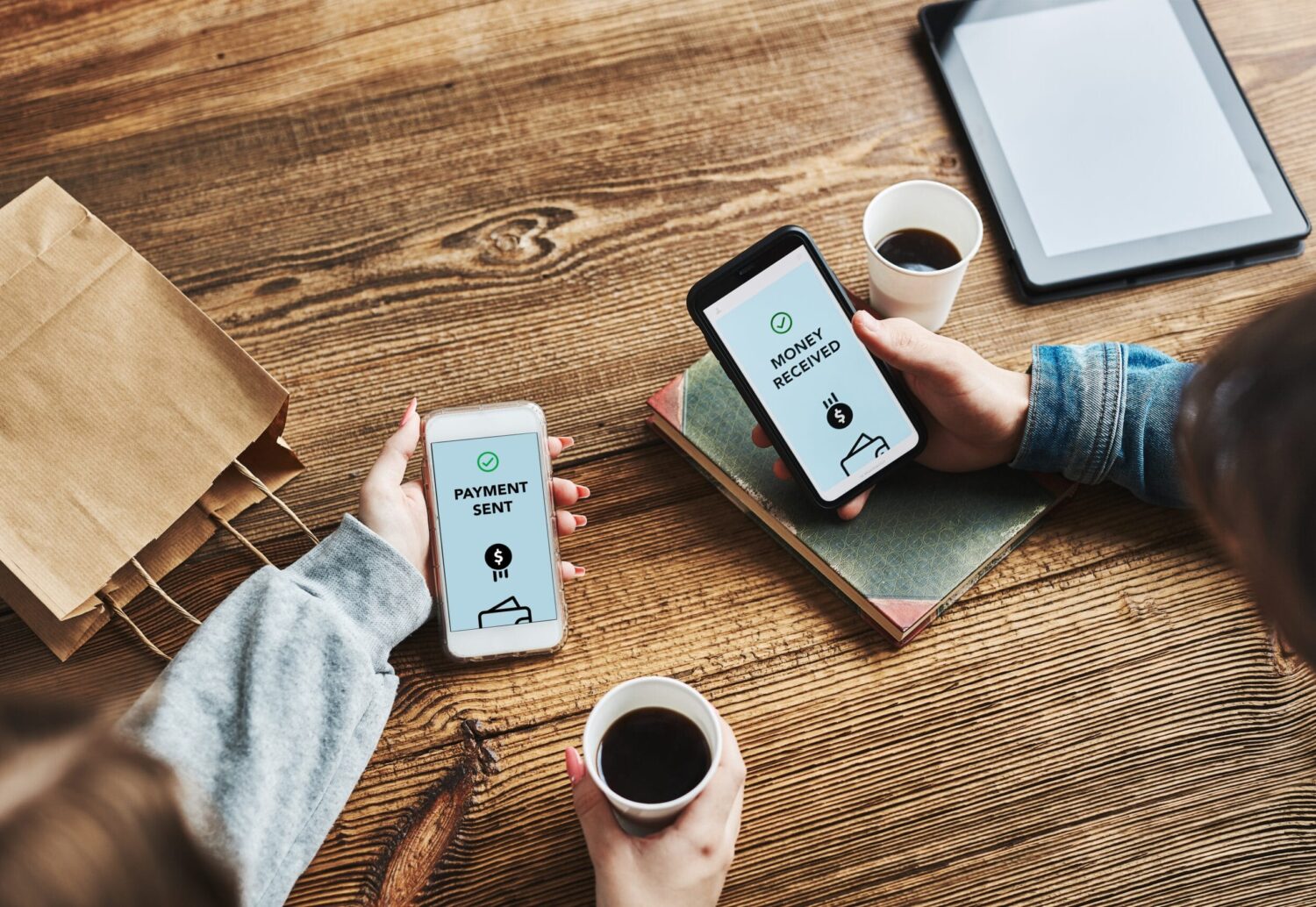 image shows two people's hands with coffee and each holding a phone trying to submit a remote payment