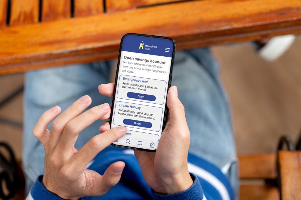 Photo shows a close up phone screen in hands, screen shows nudges to set up savings goals for emergency fund and dream holiday